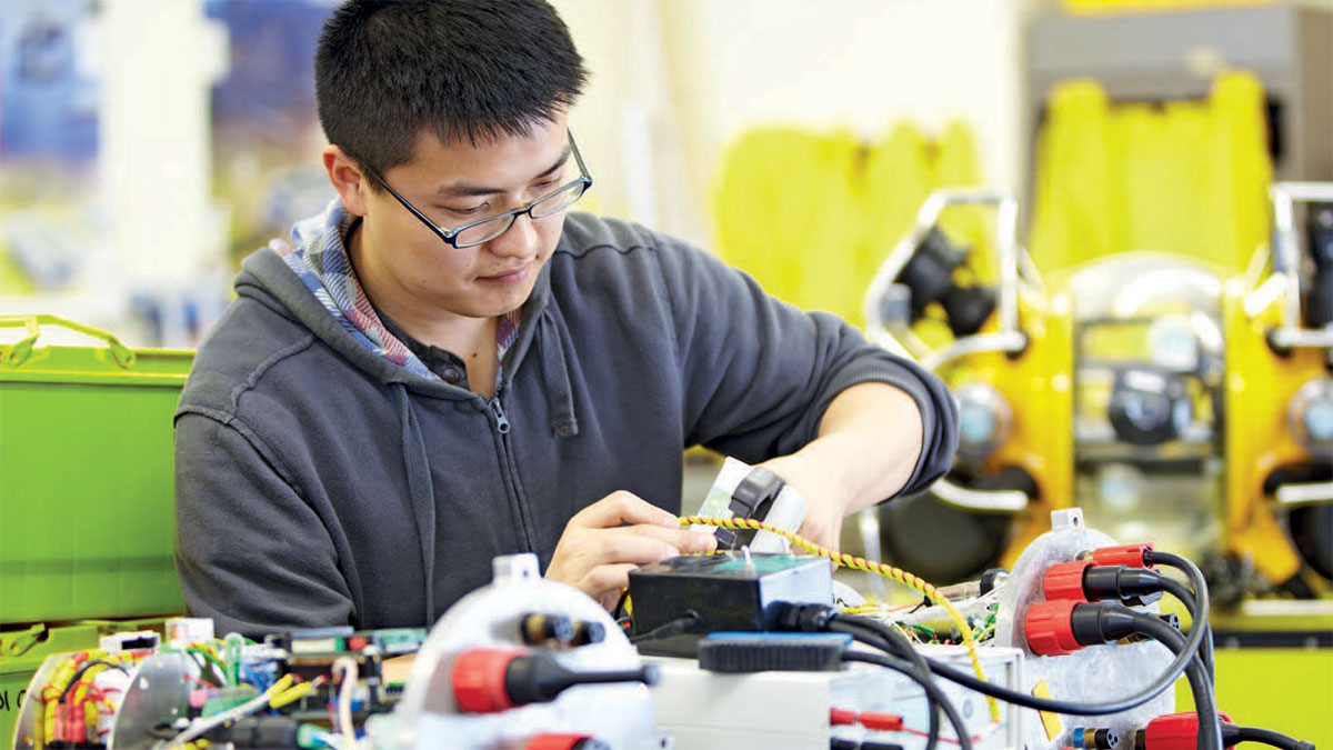 Male student doing technical assignment in workshop