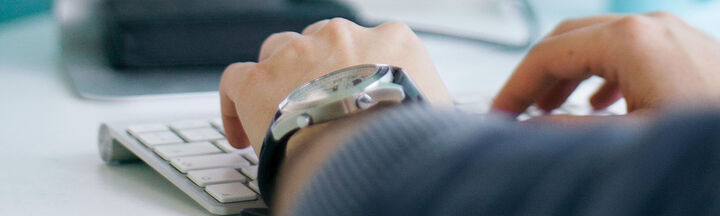 Close up of a man's hands using a desktop computer keyboard.