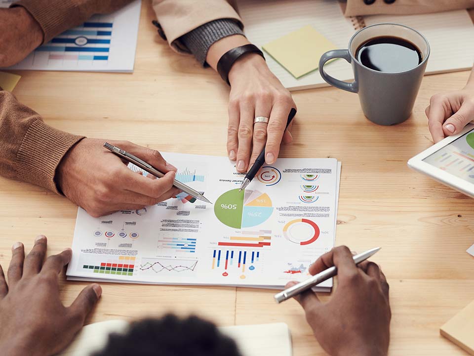 A group discuss some performance charts and tables around a table