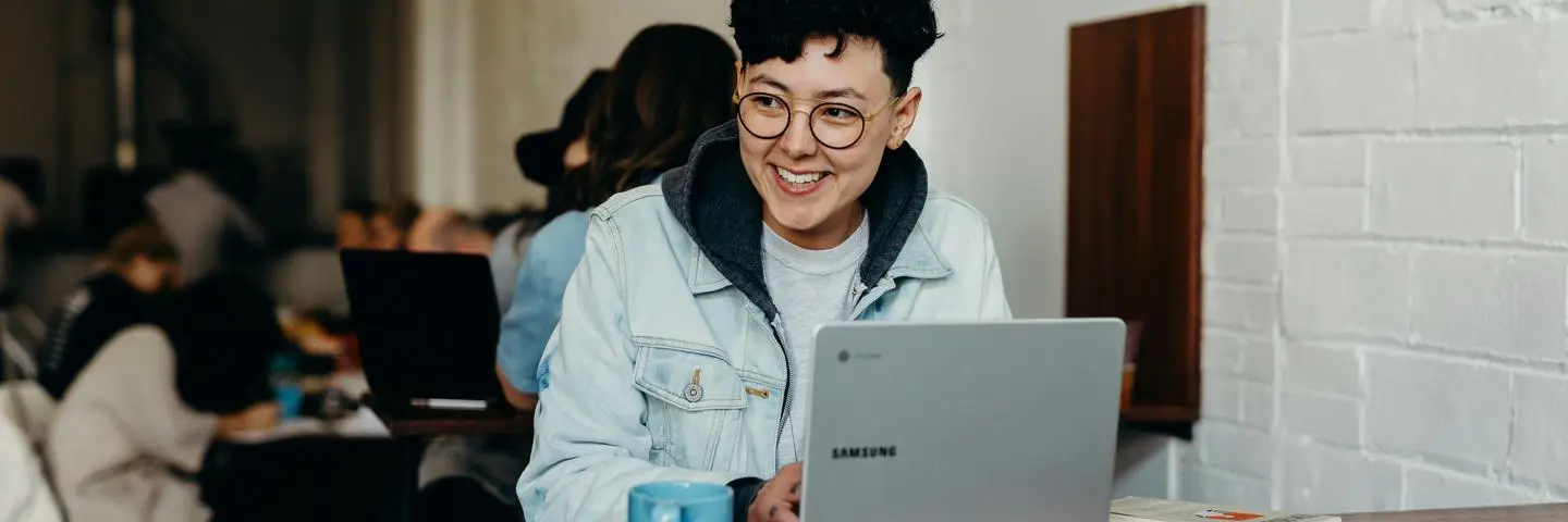 A student with a laptop sitting in a busy space
