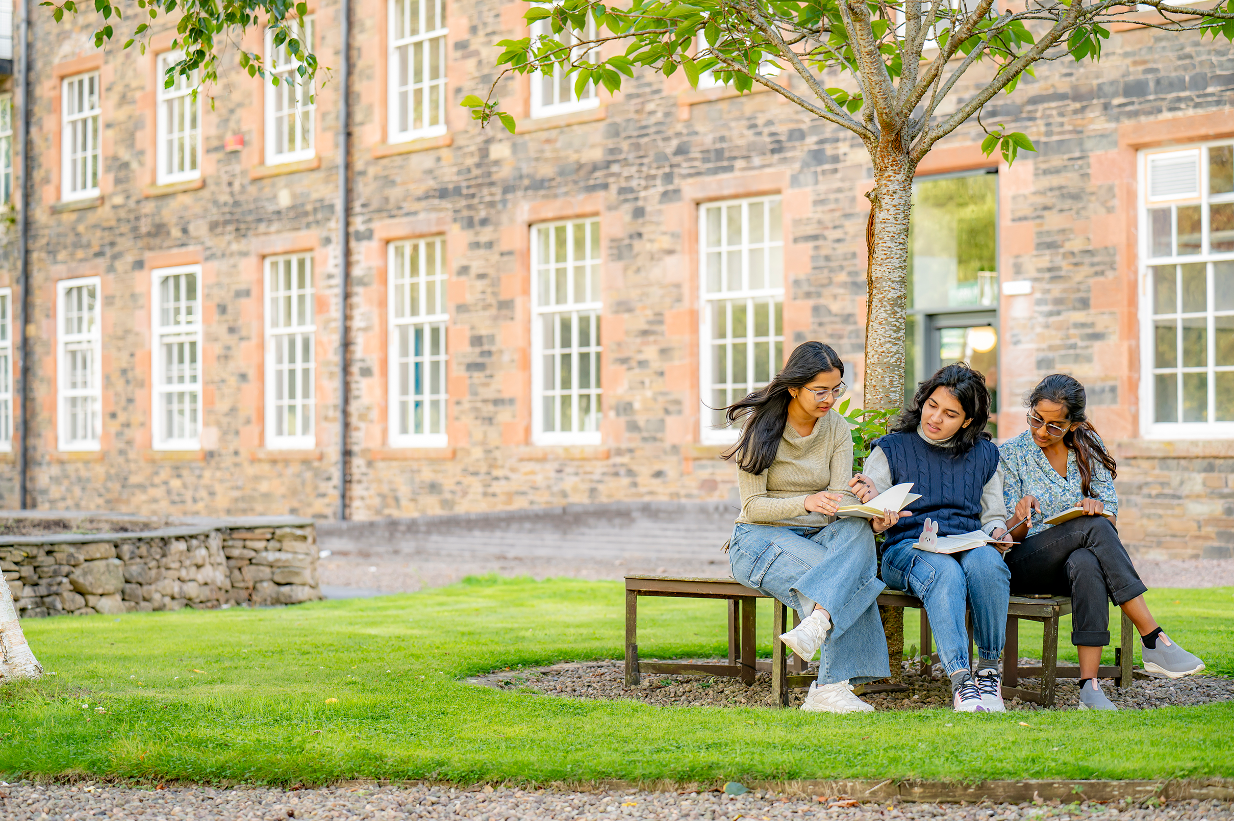 3 female students sitting outside the High Mill 