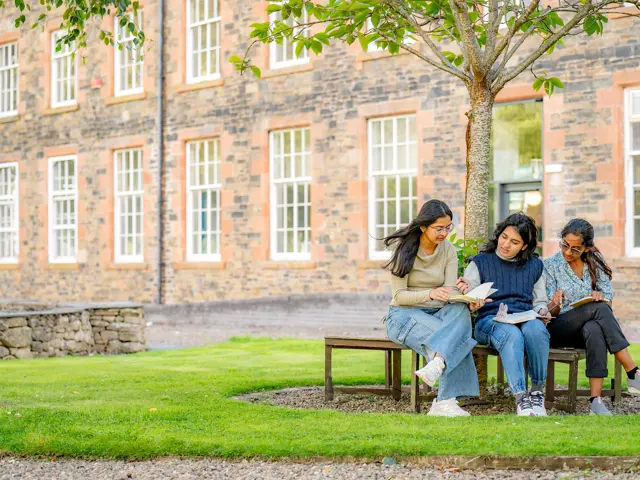 3 female students sitting outside the High Mill