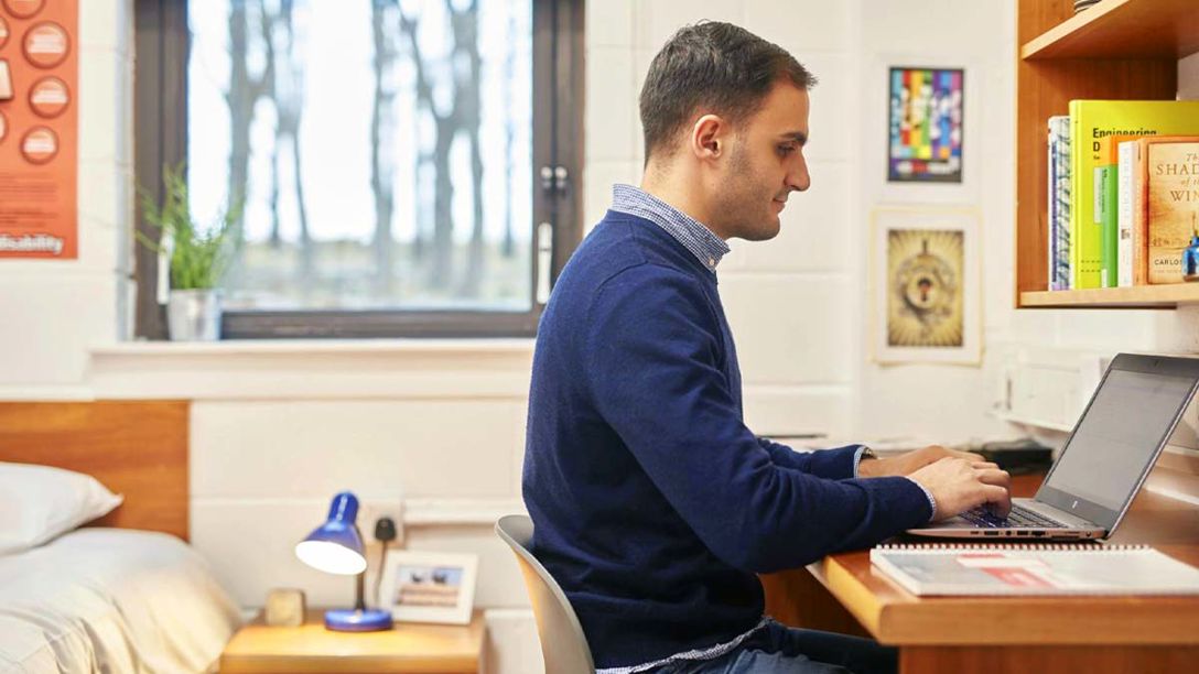 Student working on laptop in bedroom