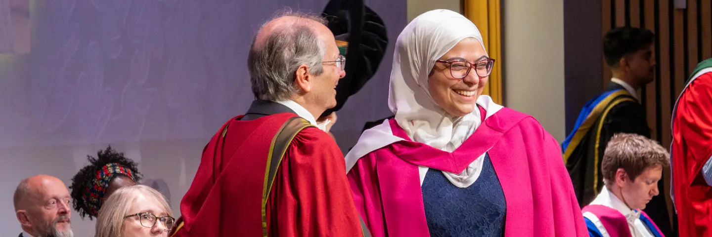 A PhD graduate receives her graduation certificate at the graduation ceremony.