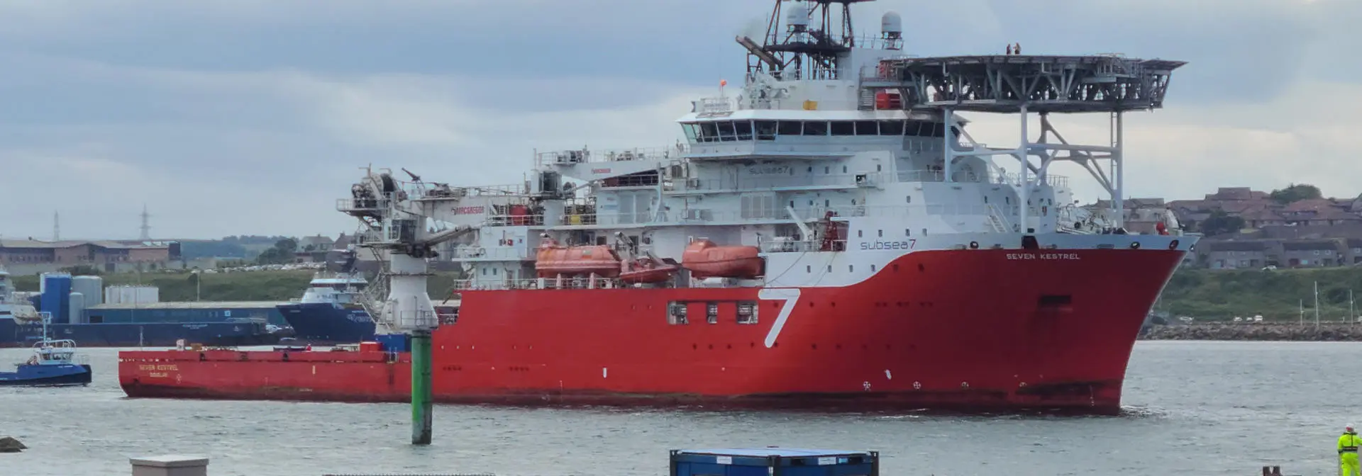A large red and white ship anchored in calm water.