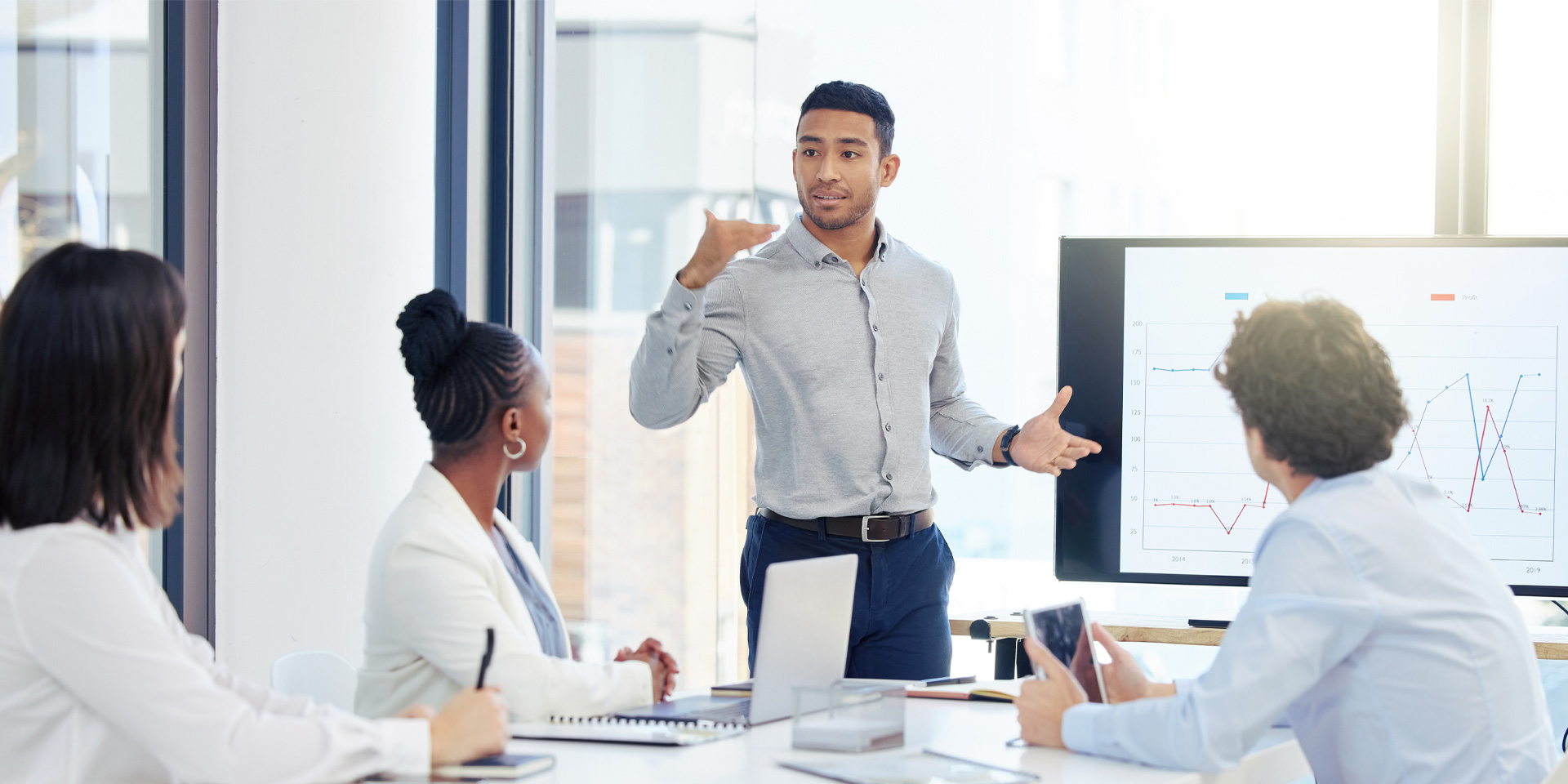 A man presenting to a group of colleagues in a conference room, engaging them with visual aids.