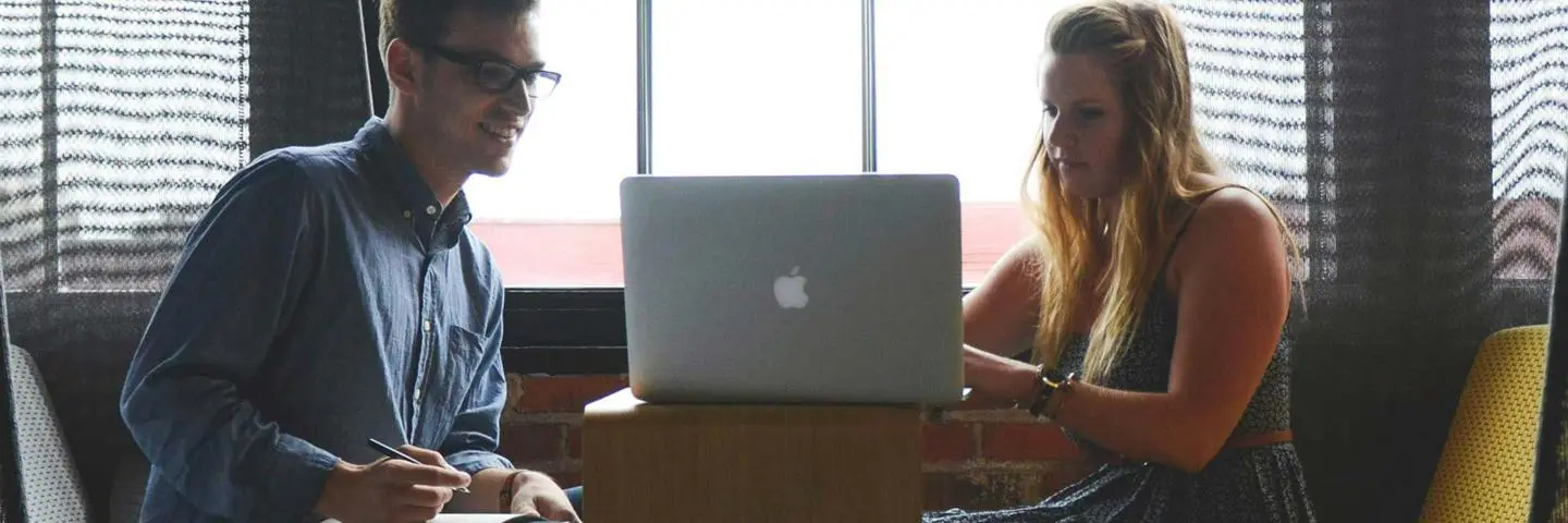 Two students work together on a laptop