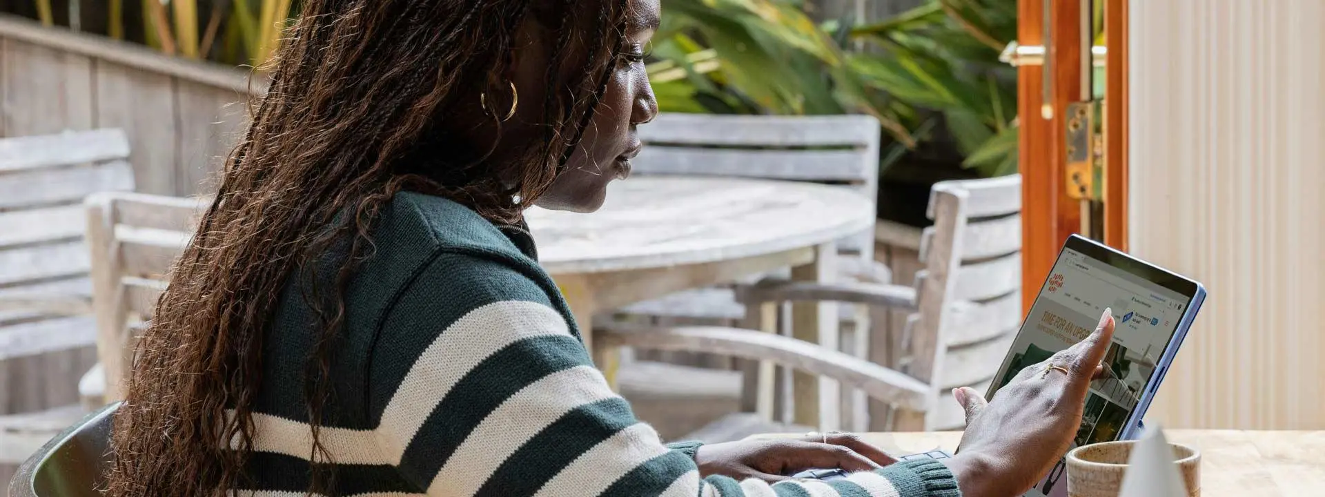 A woman seated at a table, focused on her laptop.