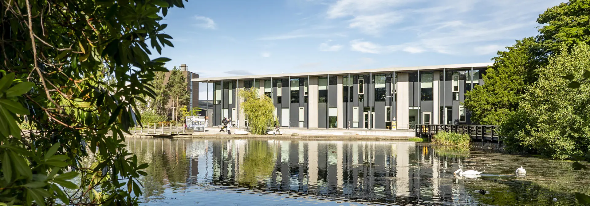 the GRID building reflecting on a serene Loch, surrounded by lush greenery.