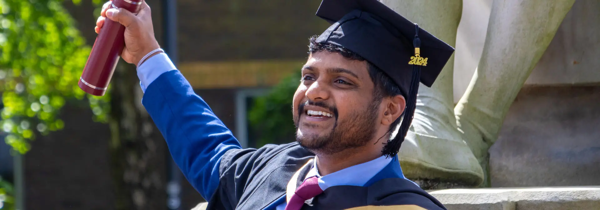 A man holds up a certificate holder on graduation day