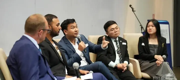 Panel of speakers sitting around table with microphone