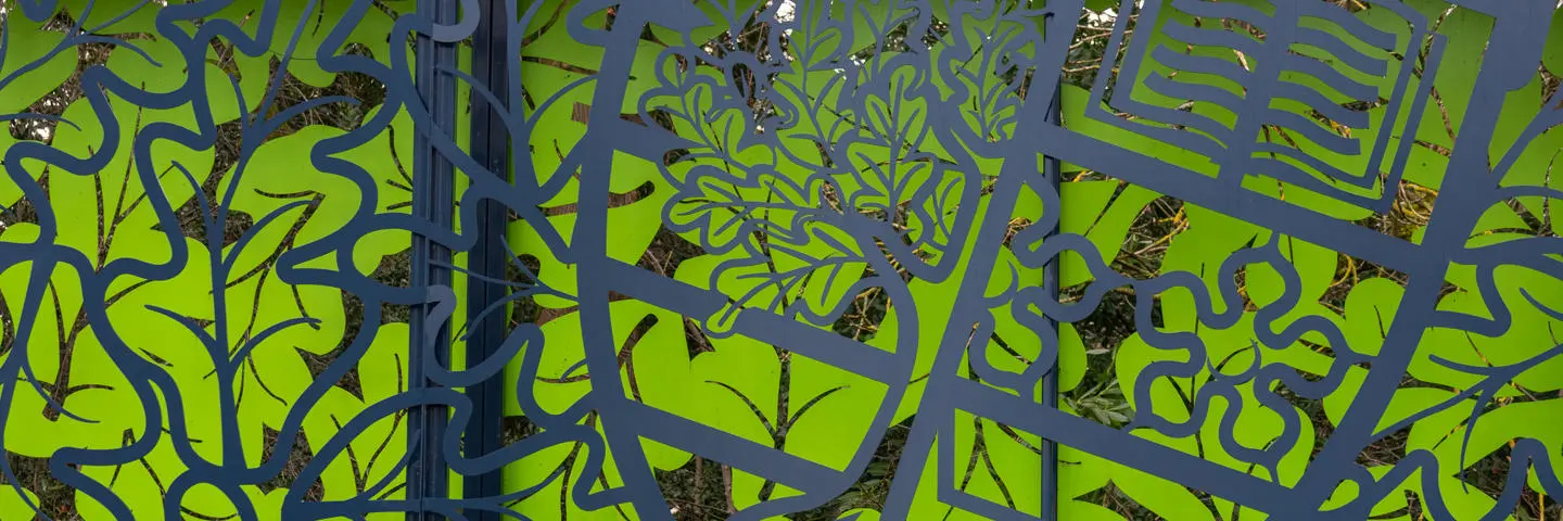 A decorative outdoor metal fence featuring a green background.