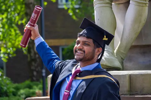 Graduate smiling and waving degree