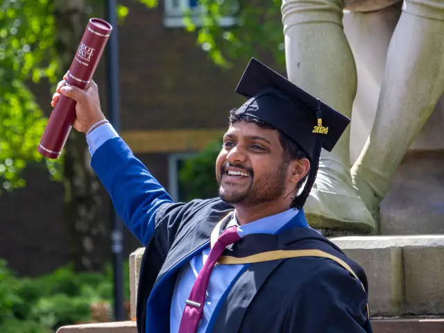 Graduate smiling and waving degree