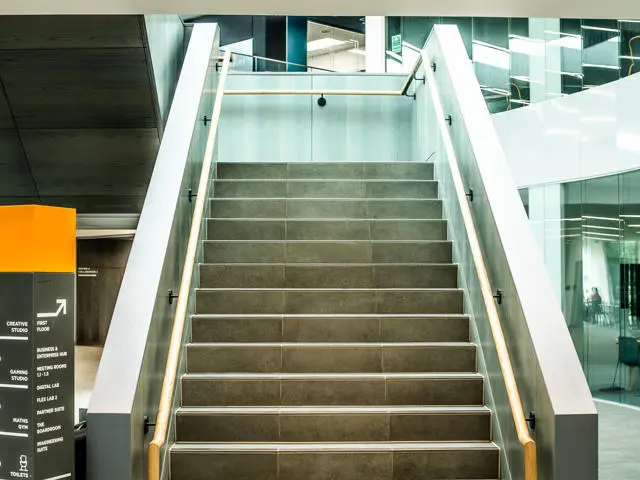 Stairs leading upwards with rails on either side, and a clear signpost to the left of the stairs.