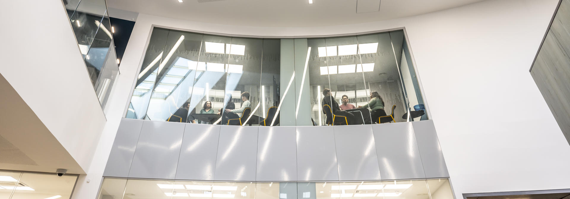 Shot of the inside of the Heriot-Watt GRID building, with a view up from below to glass windowed meeting rooms