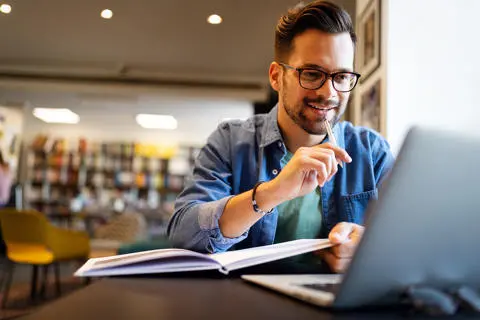 Man working on a laptop in a library.