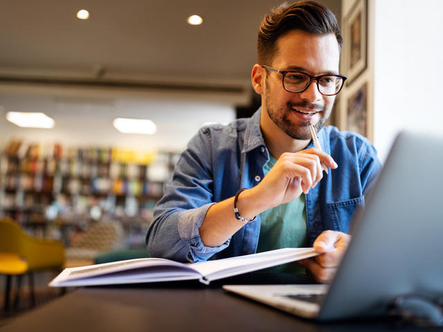 Man working on a laptop in a library.