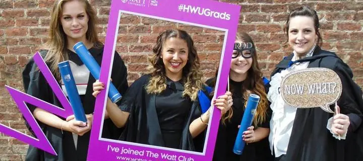 Graduates holding sign reading "I've joined the Watt Club"