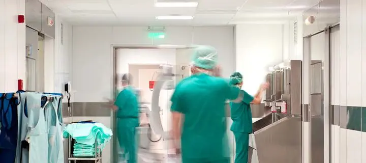 Hospital doctors wearing green protective clothing, hair coverings and face masks.