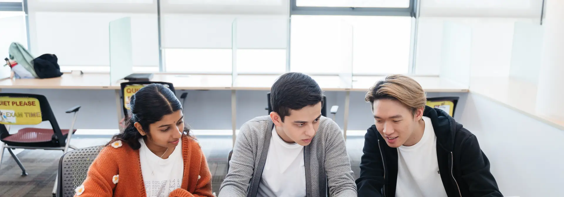 Three students sitting at a desk.