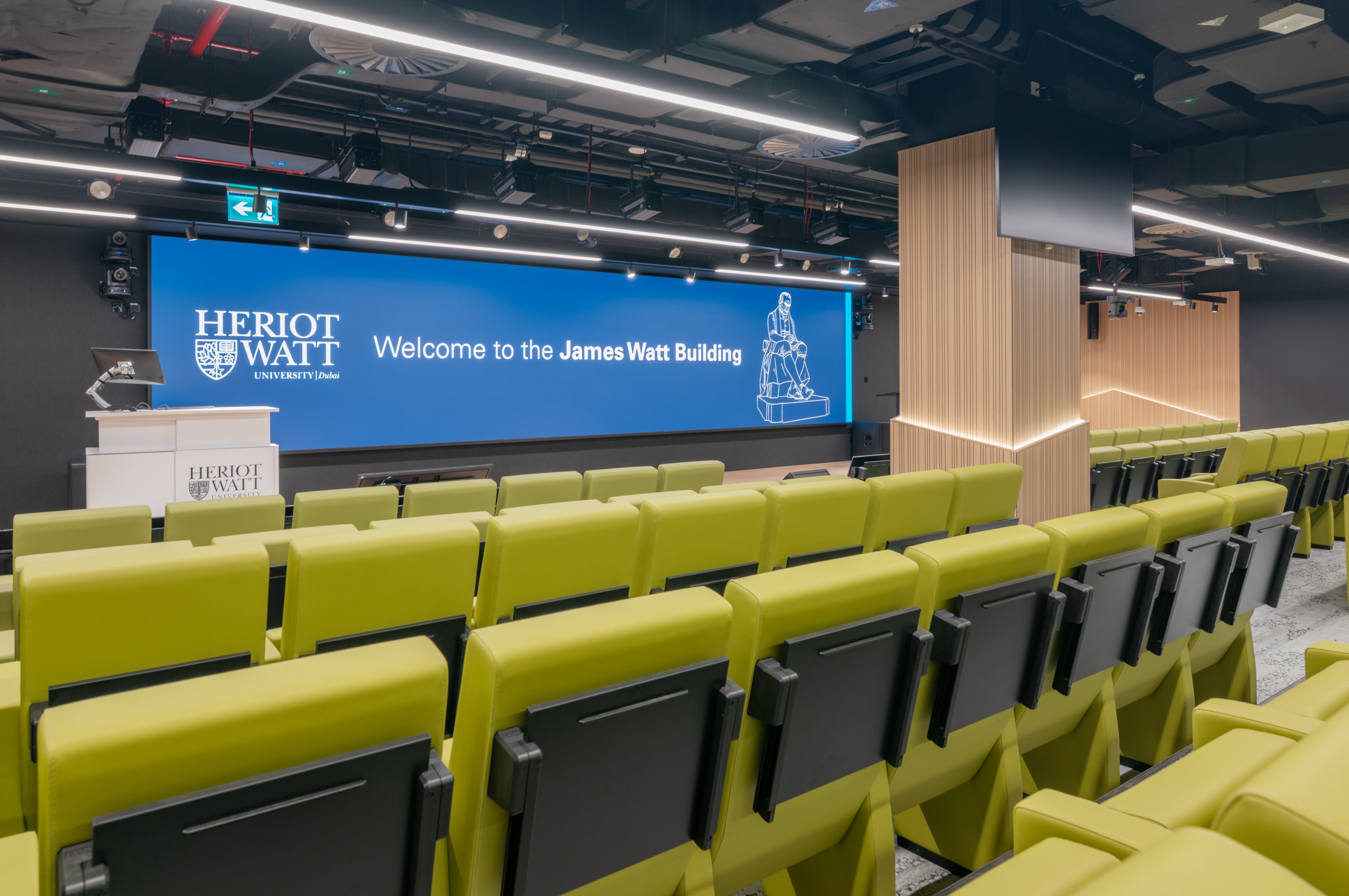 auditorium stage with video wall infront of green folding seats