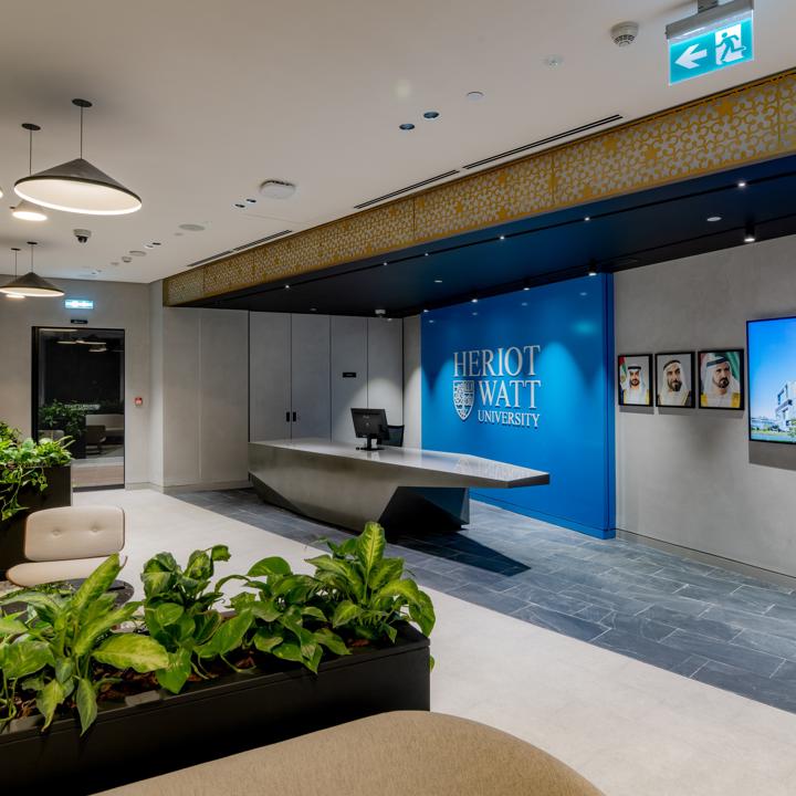 reception with a grey stone desk infront of wide blue panel with Heriot-watt logo