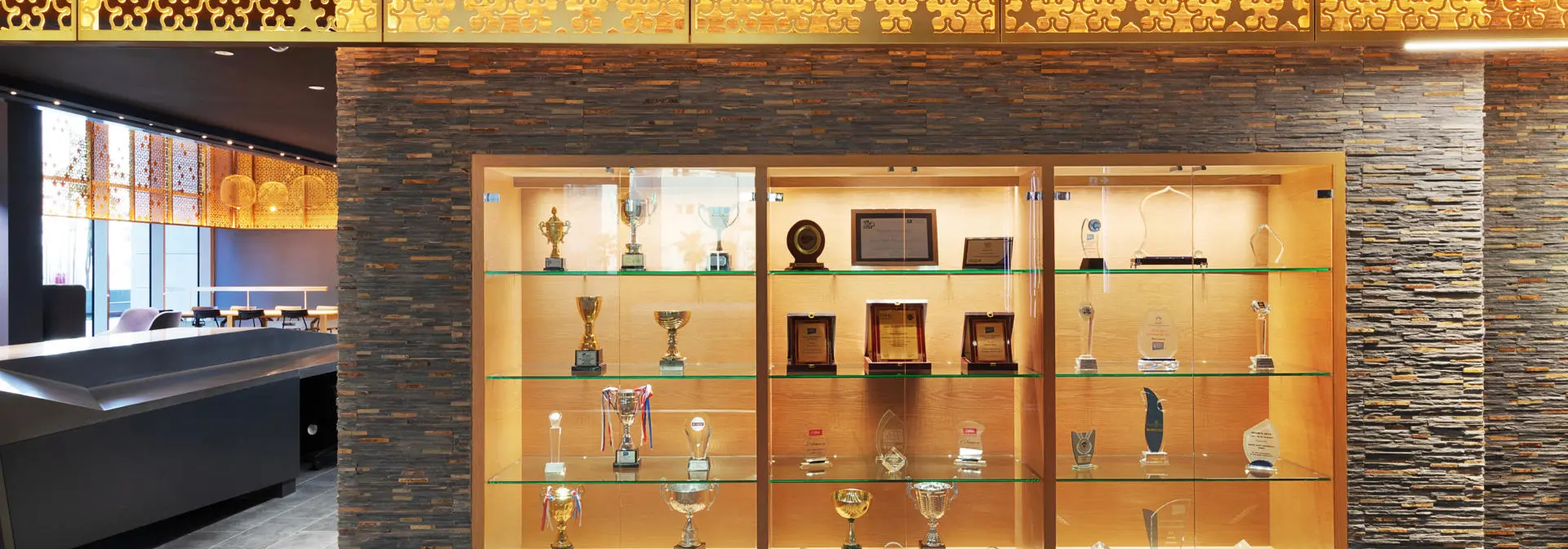 A wooden brown display case with trophies on shelves.