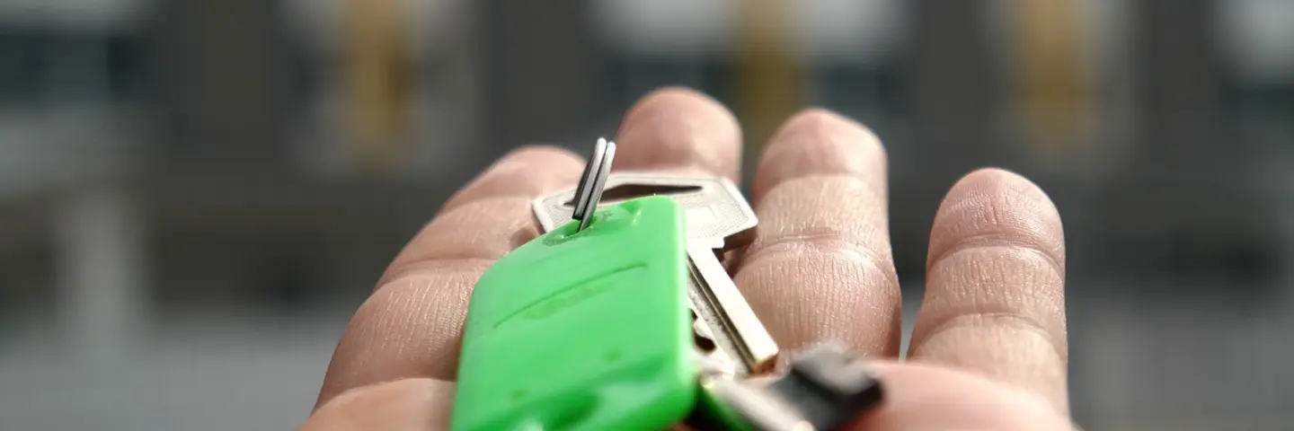 Hand holding a set of keys with green tag