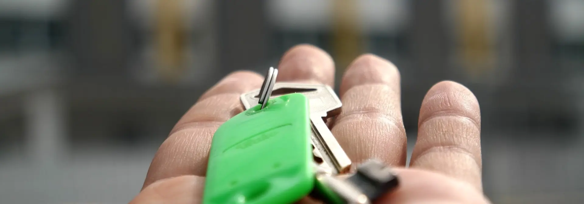 Hand holding a set of keys with green tag