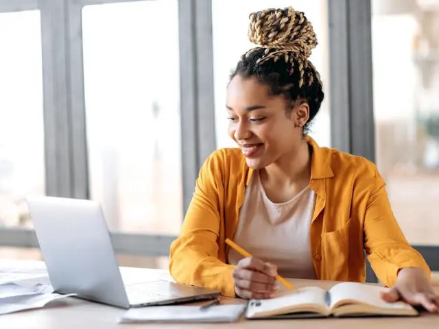 Woman works from home at a computer writing notes