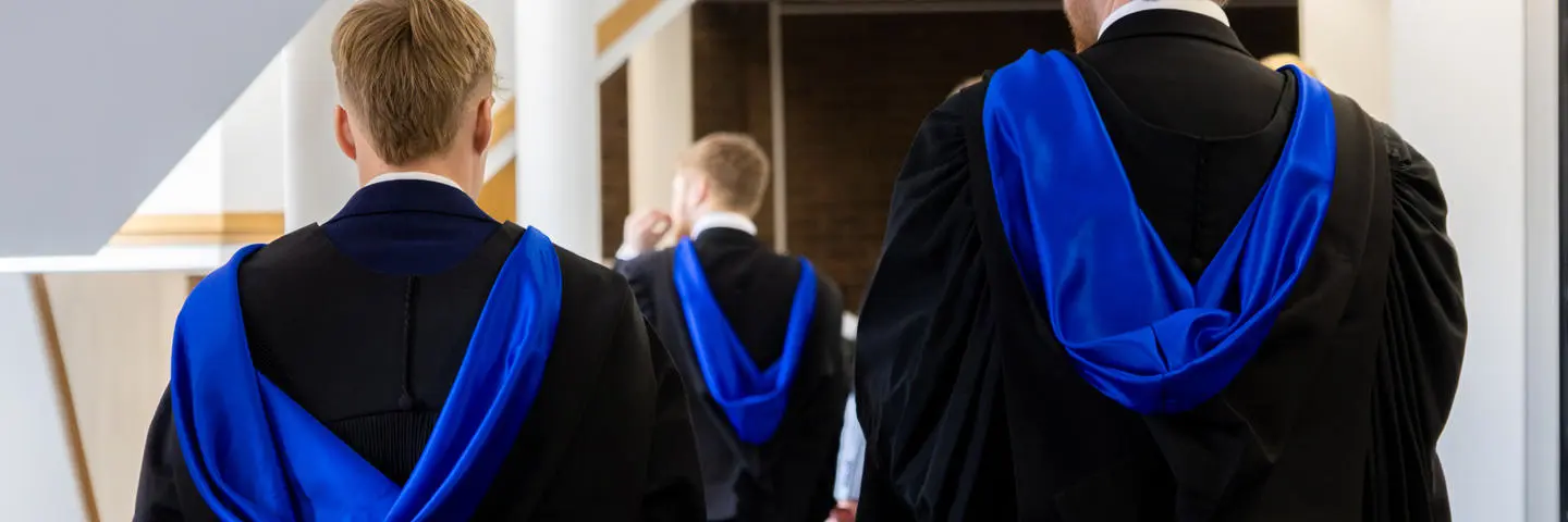 Graduates in gowns walking down hall