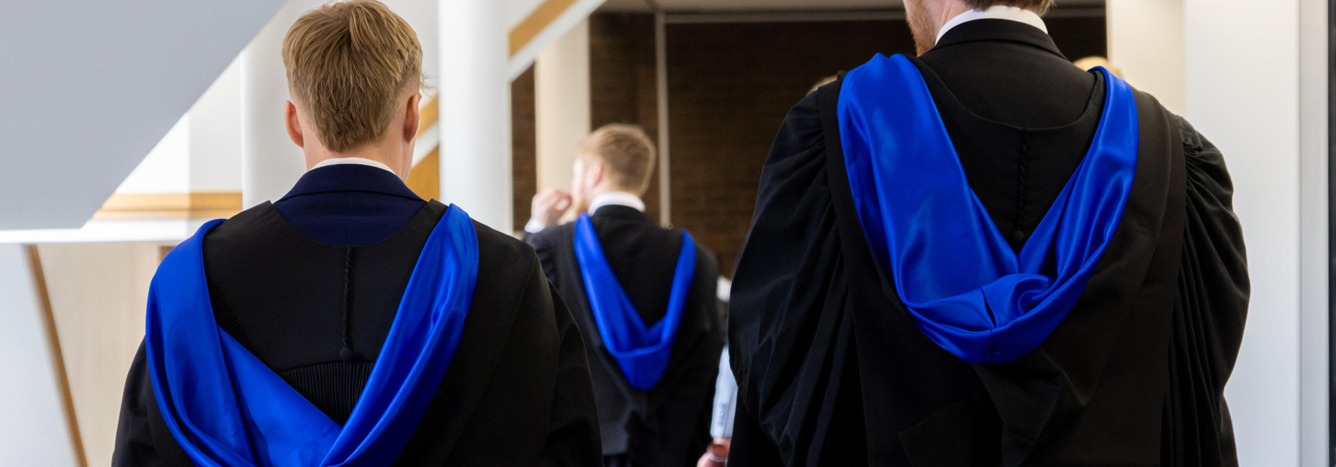 Graduates in gowns walking down hall