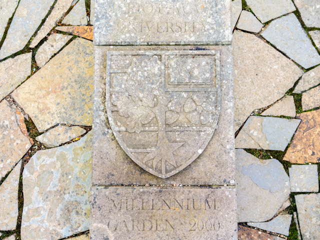 Close up picture of the millenium garden plaque inlaid on stone paving with the Heriot-Watt shield symbol.
