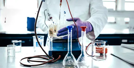 Student with beakers and chemistry apparatus doing an experiment
