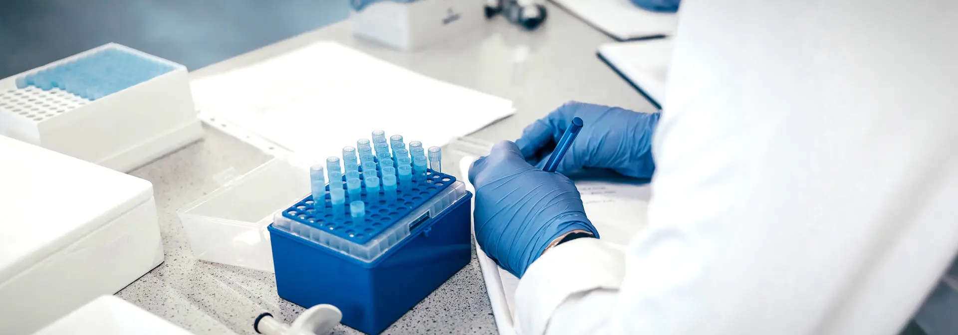 Students in a laboratory document sample details in a notebook.