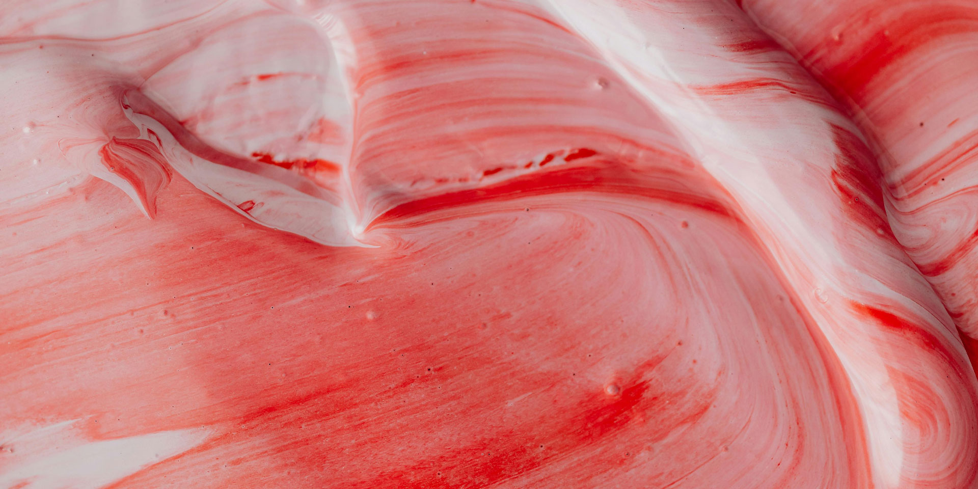 A close-up of a red and white mixture swirling together.