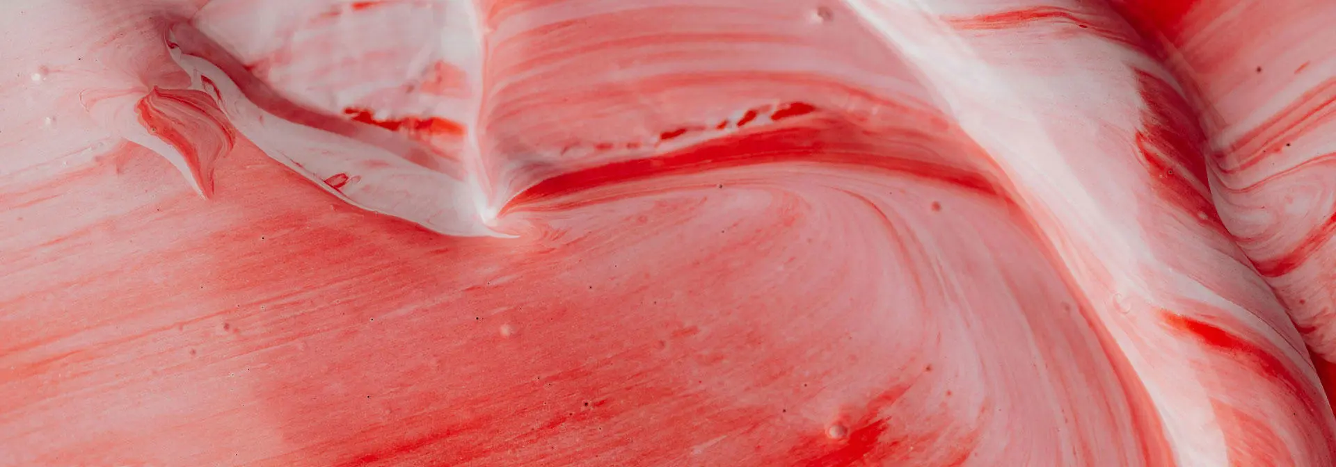 A close-up of a red and white mixture swirling together.