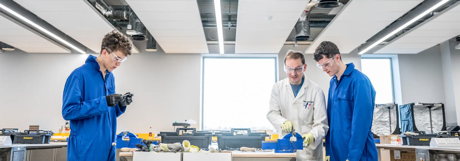 A professor guiding students on equipment use in maker lab