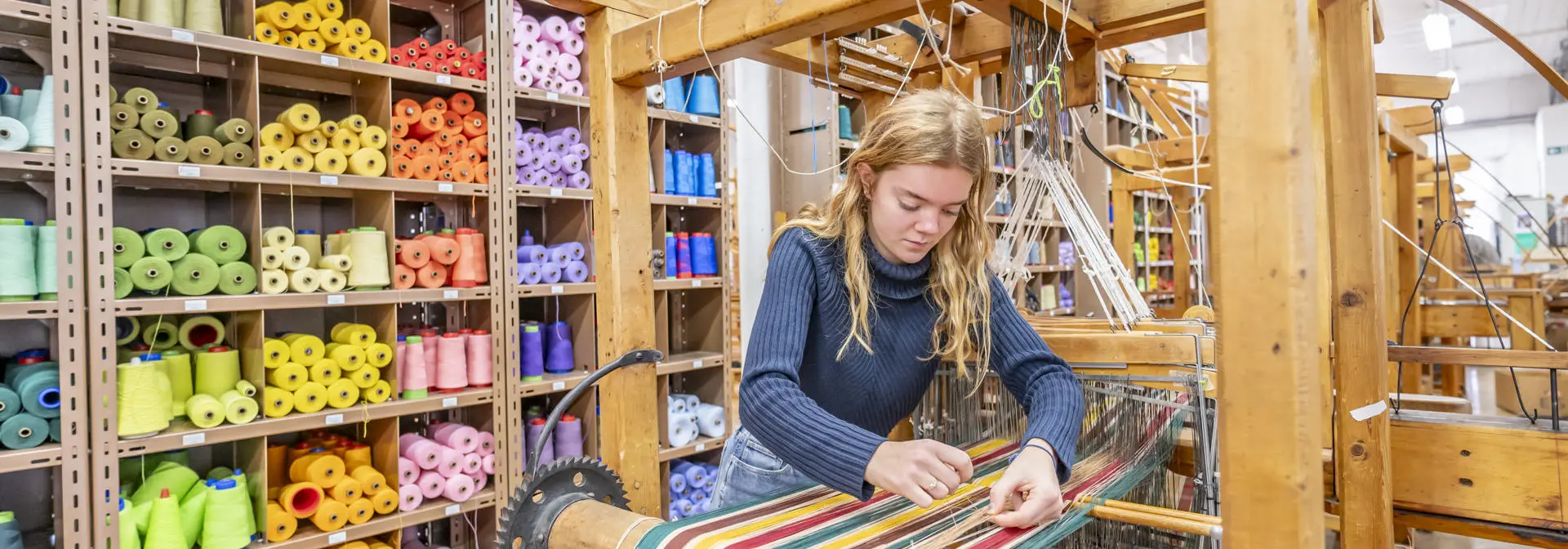 Textiles student working with a loom in the Weave Shed