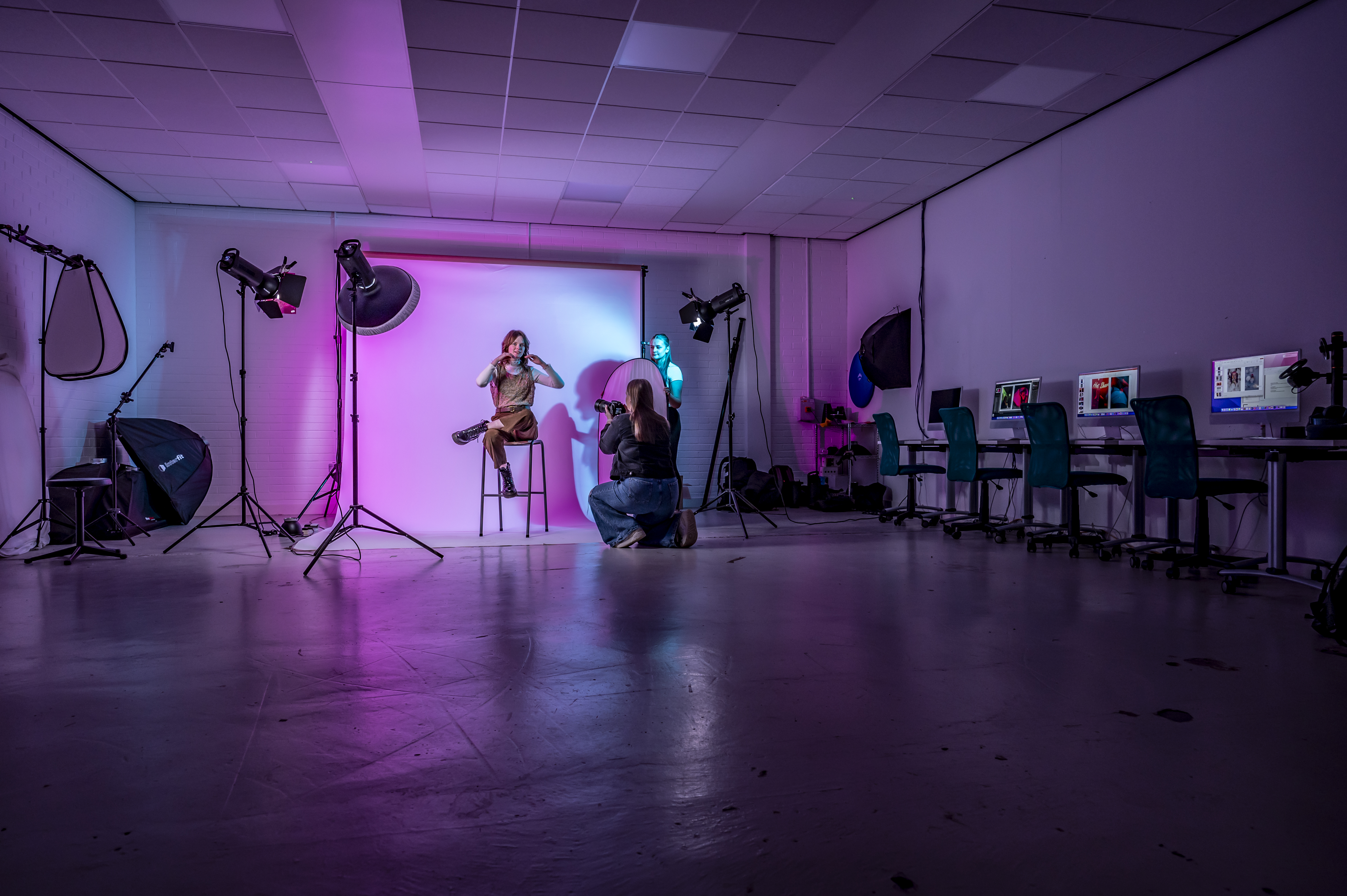 Textile and Design students taking photographs of a model against a white screen.