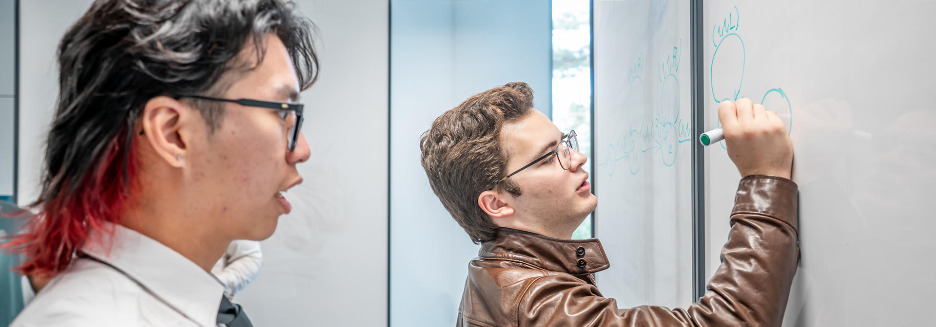 Students writing on a whiteboard and working on a question