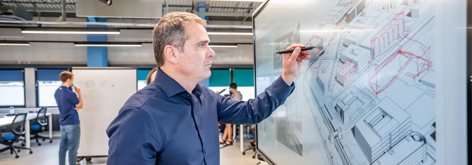 Person writing over a 3d model of buildings in a monitor