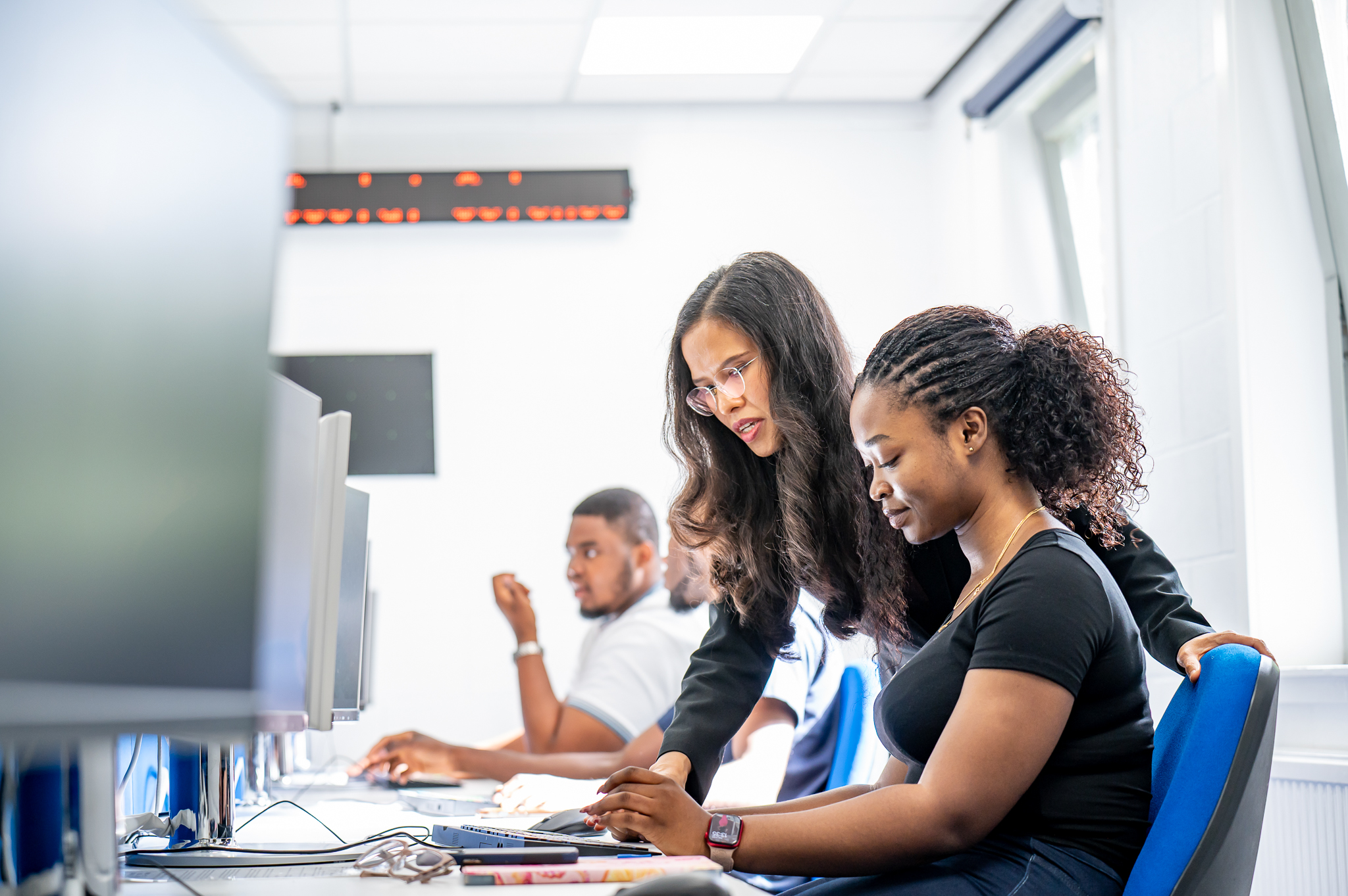 Students working with a professor in a finance lab