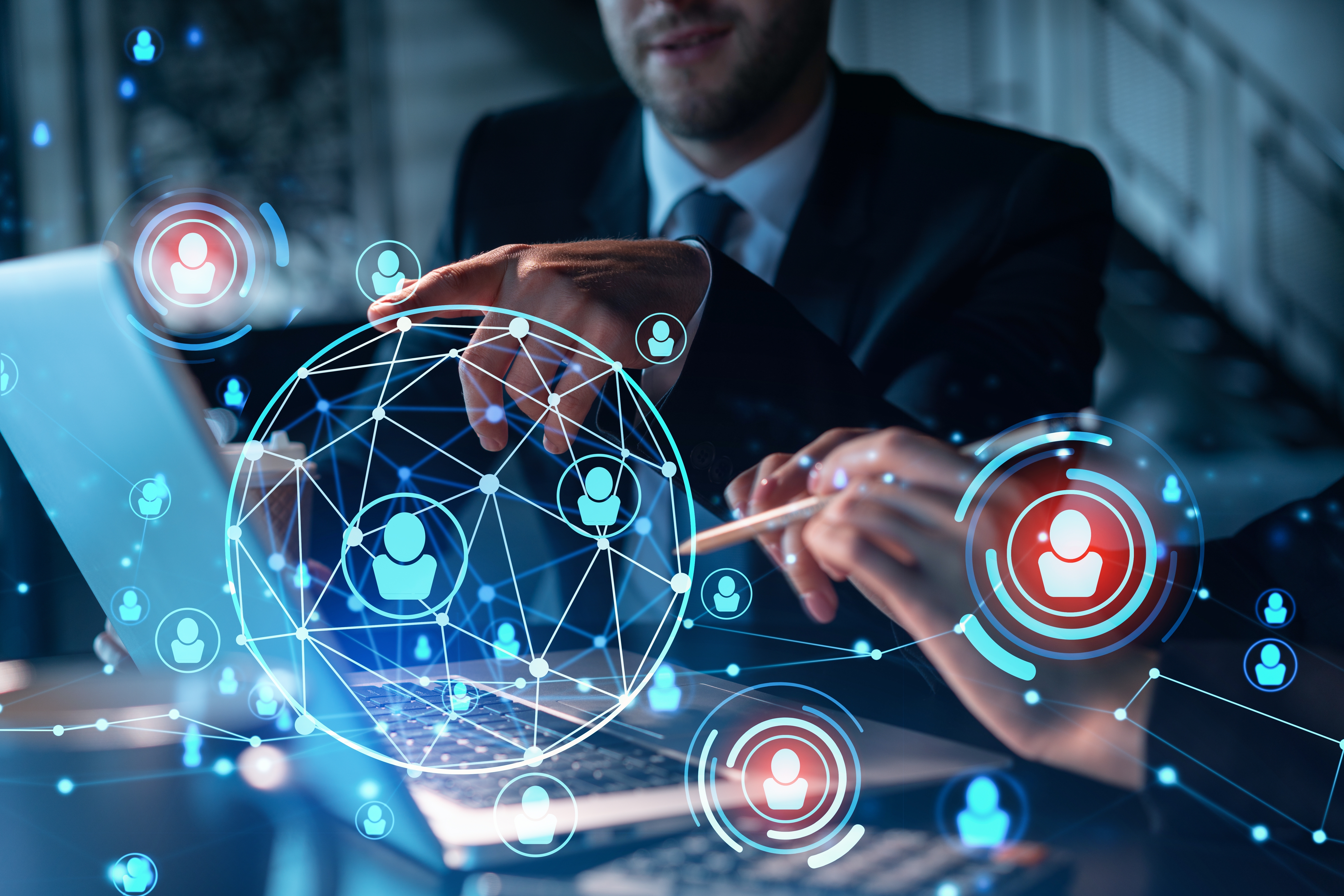 Two individuals collaborate at a laptop, with digital icons representing people and management