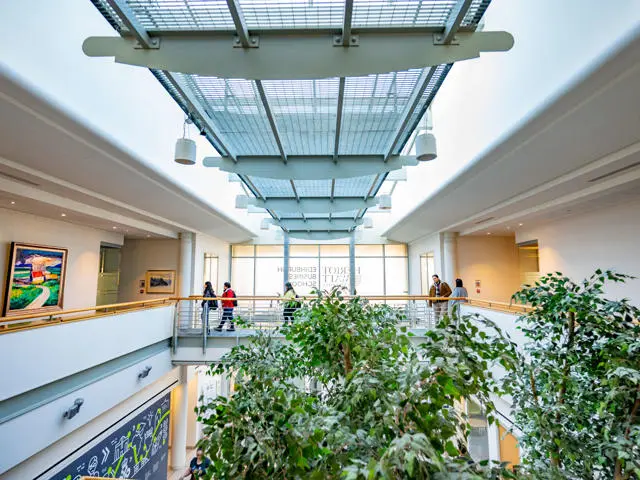 Students walk across the mezzanine floor walkway in Edinburgh Business School