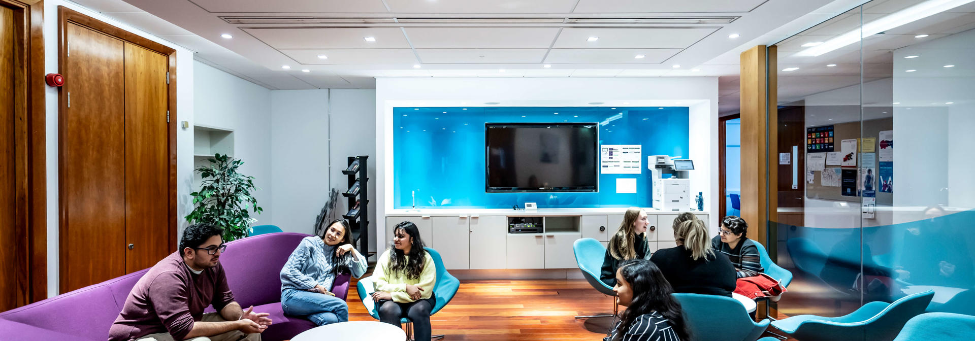 Two groups of students seated in a break out area in conversation