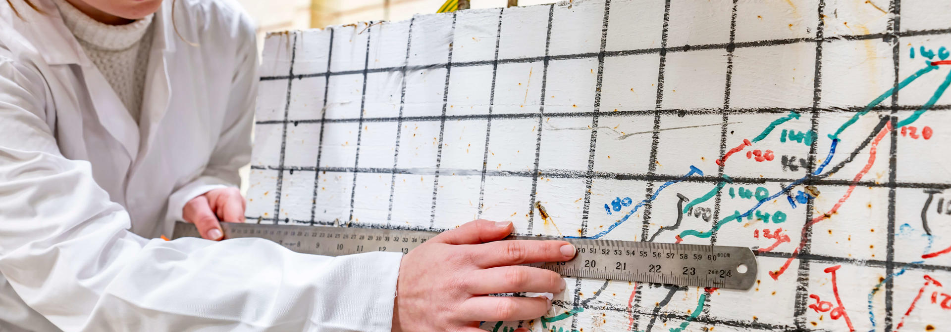 A student using a metal ruler on a piece of material that has been crushed by a pneumatic press