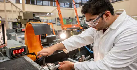 Student using engineering machinery in an industrial lab.