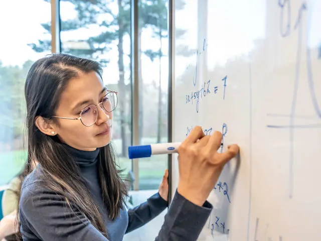 Mathematics student woman writes on a whiteboard